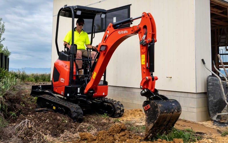 Compact mini-excavator working in a residential backyard